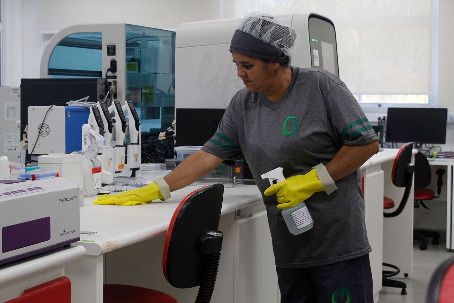 Custos operacionais vs despesas operacionais: entenda as diferenças Colaboradora limpando laboratório com eficiência, ilustrando custos operacionais em contraste com despesas.