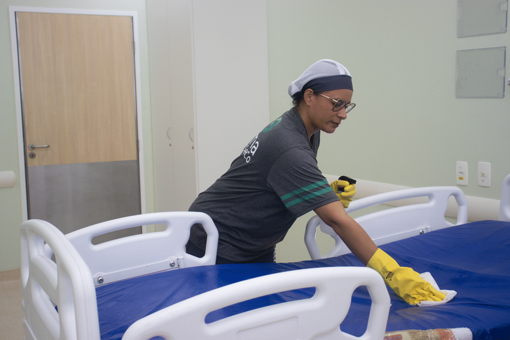 Limpeza de leito hospitalar com luvas e pano de higienização.